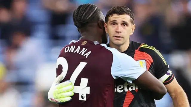 Emiliano Martinez of Aston Villa interacts with Amadou Onana