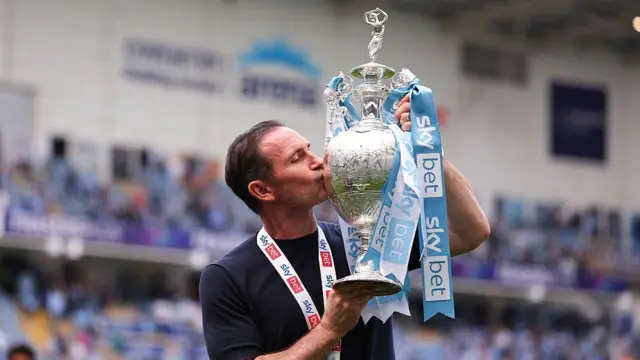 Frank Lampard in a dark blue t-shirt kisses the Championship trophy