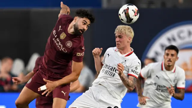 Manchester City and AC Milan players challenge for the ball