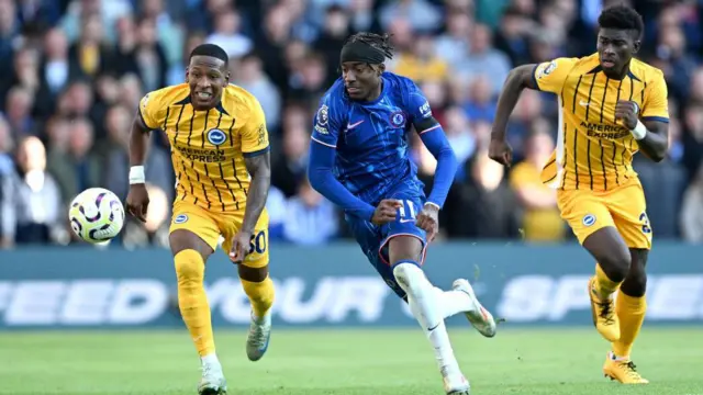 Noni Madueke of Chelsea runs ahead of Pervis Estupinan and Carlos Baleba of Brighton & Hove Albion during the Premier League match between Chelsea FC and Brighton & Hove Albion FC at Stamford Bridge