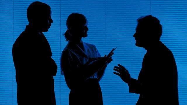 Two businessmen and a businesswomen talking - in silhouette