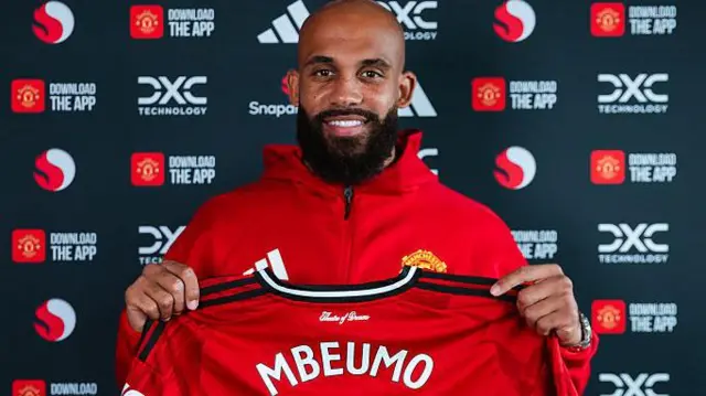 Bryan Mbeumo holding a Manchester United home shirt