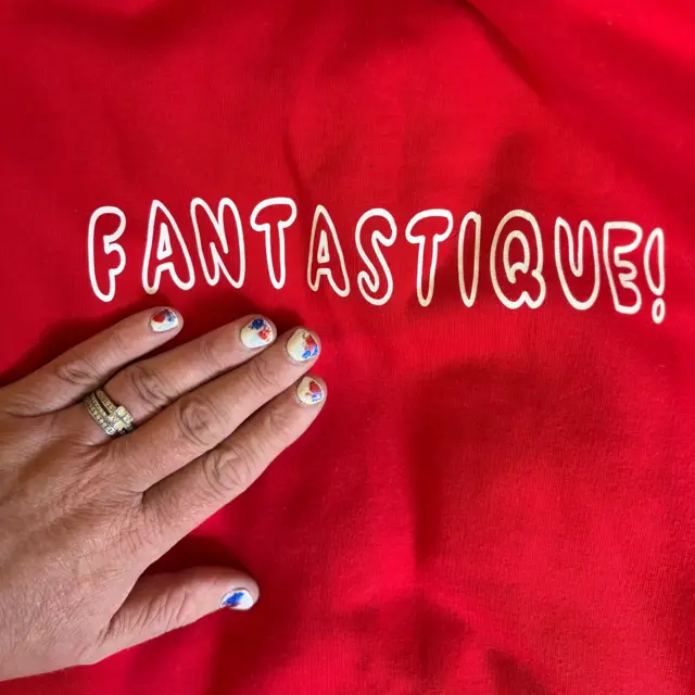 A woman with a red sweatshirt and Crystal Palace nails