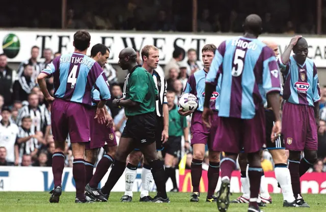 Referee Uriah Rennie walks past Alan Shearer having just sent the Newcastle striker off against Aston Villa in August 1999. Several Villa players, including Gareth Southgate, Colin Calderwood and Ian Taylor are crowded around. 