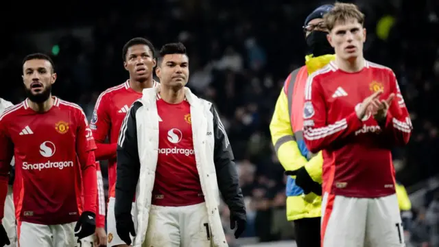 Manchester United players applaud supporters at full-time.