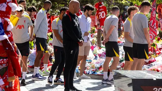 Liverpool players and boss Arne Slot stand silently among the floral tributes around Anfield
