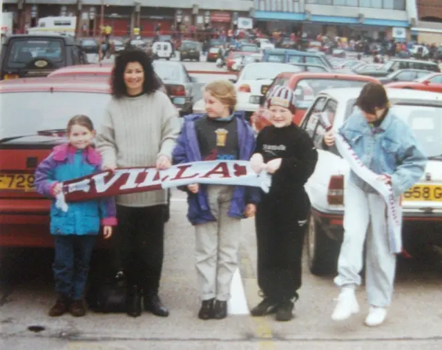 Gary and his family holding an Aston Villa scarf in front of the stadium 