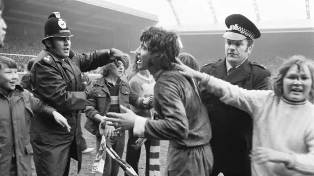 Police try to stop Kevin Keegan from being mobbed by fans on the pitch at Anfield