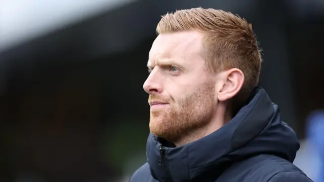 A close-up of Ed Still wearing a navy blue zip up jacket