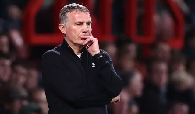 Phil Parkinson looks thoughtful with fingers pressed to his lips and face on the touchline