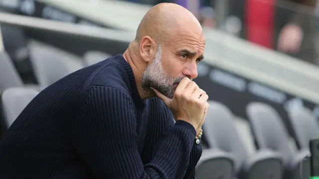 Pep Guardiola looks on thoughtfully from seat