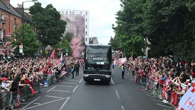 Fans react as the Arsenal team bus arrives at the stadium