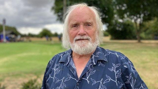 Graham Hardy stands in a field, smiling at the camera
