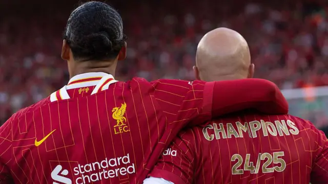 Virgil van Dijk has arm over shoulder of Arne Slot as they look on after winning title