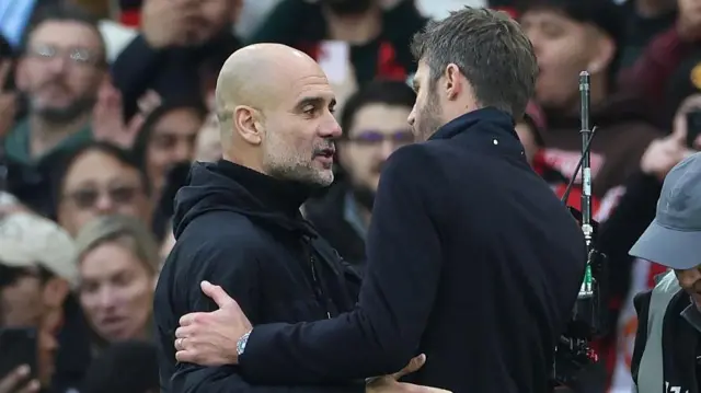Pep Guardiola and Michael Carrick embracing on the touchline