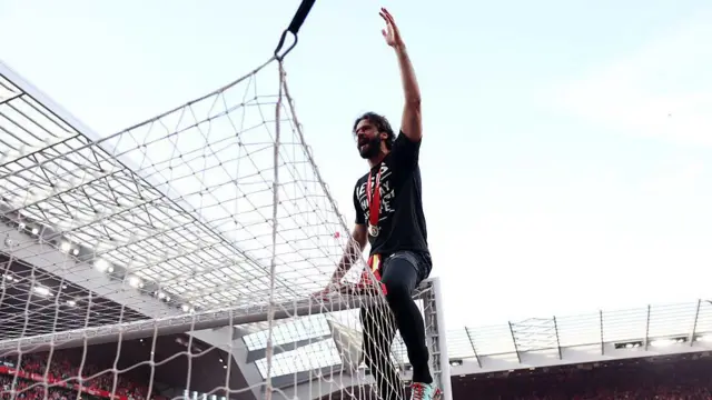 Alisson Becker of Liverpool celebrates on top of the goal