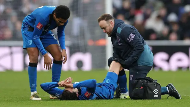 Enes Unal lying on his back injured with his hands on his head