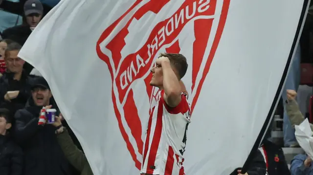 Dan Ballard celebrates in front of a Sunderland flag
