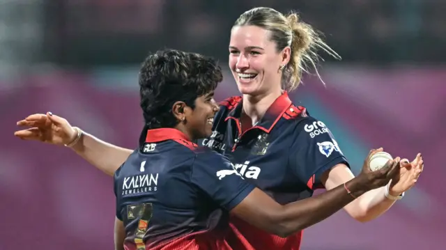 Royal Challengers Bengaluru's Lauren Bell (R) celebrates with team-mate Arundhati Reddy 