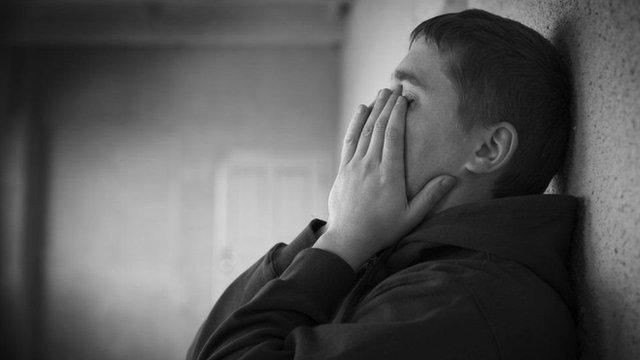 A teenage boy holding his head in his hands