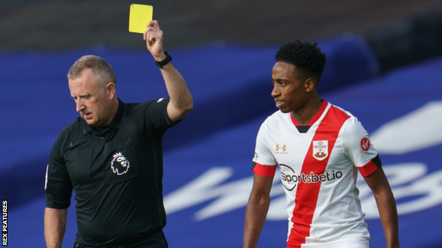 Referee Jonathan Moss shows Kyle Walker-Peters a yellow card