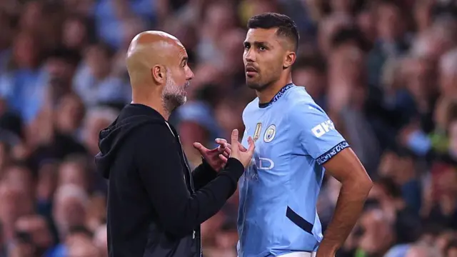 Manager of Manchester City Pep Guardiola talks to Rodri