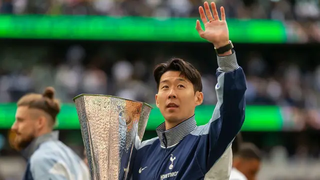 Son Heung-min waves to fans while holding Europa League trophy