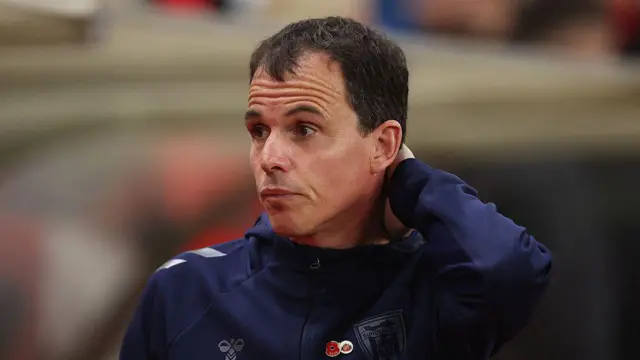Regis le Bris, wearing a dark Sunderland top, standing on the touchline during a game with his hand on the back of his neck