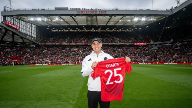 Manuel Ugarte holds his shirt up in front of a packed crowd at Old Trafford