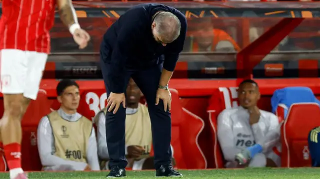 Ange Postecoglou bending down on the touchline