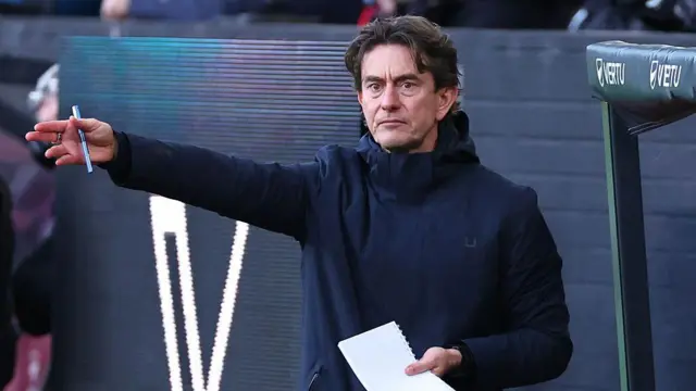 Thomas Frank gestures on the sideline while holding a pen and notepad