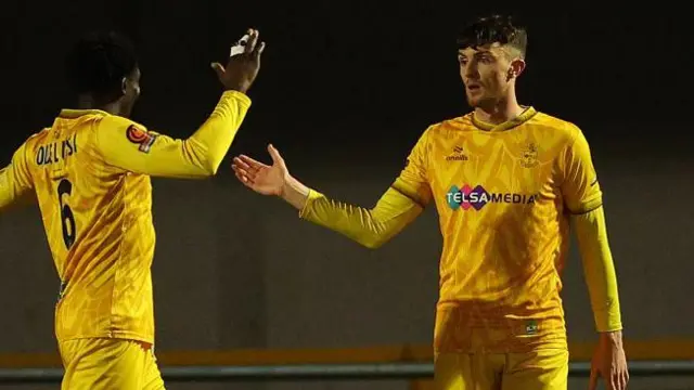 Alex Kirk (right) is congratulated by Siju Odelusi after scoring for Sutton in February 2025