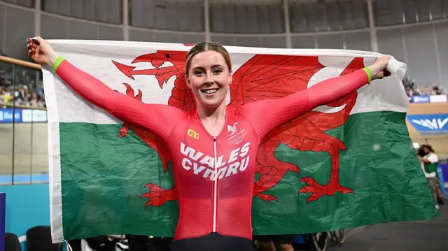 Emma Finucane carries the Welsh flag.