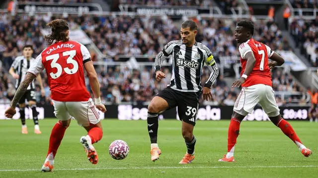Riccardo Calafiori  and Bukayo Saka of Arsenal battle for the ball against Bruno Guimaraes of Newcastle United