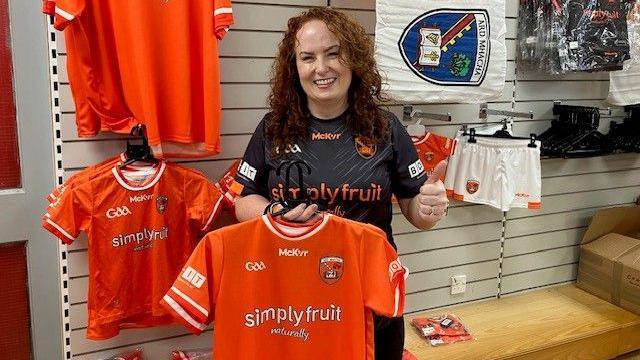 Éilis McCreesh in McKeever Sports Armagh GAA pop-up shop. Posing infront of GAA merchandise 