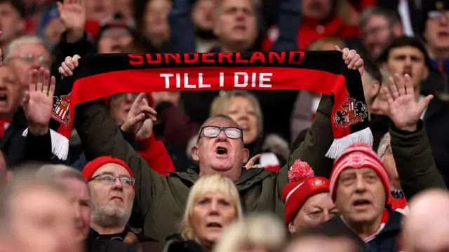  A fan of Sunderland holds up a scarf which reads 'Sunderland Till I Die'