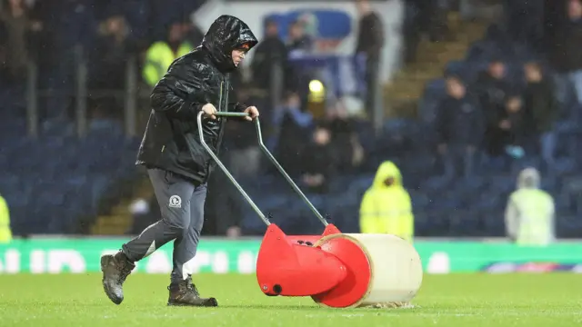 Ground staff try to remove water from the playing surface at Ewood Park during Blackburn v Sheffield Wednesday