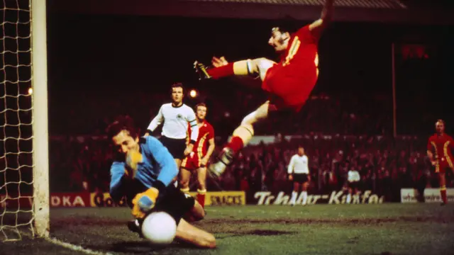 Mickey Thomas acrobatically attempts to score for Wales against West Germany at Ninian Park in 1976 with Alan Curtis and Franz Beckenbauer in the background