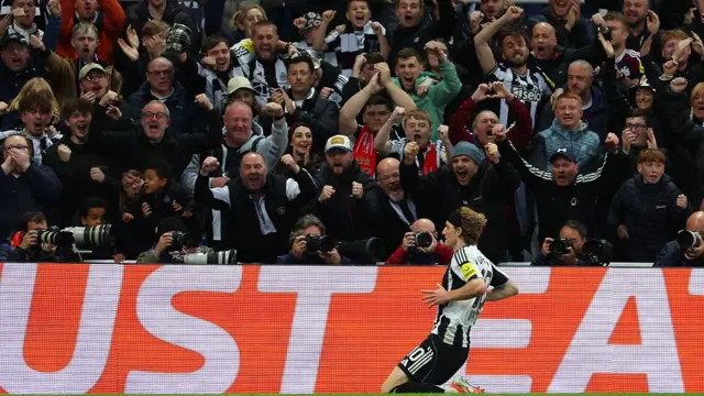 Anthony Gordon celebrates with a knee slide in front of the Newcastle fans