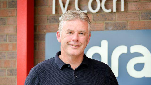 Iwan Trefor Jones, cadeirydd elusen Gafael Llaw, yn edrych tuag at y camera mewn llun portread