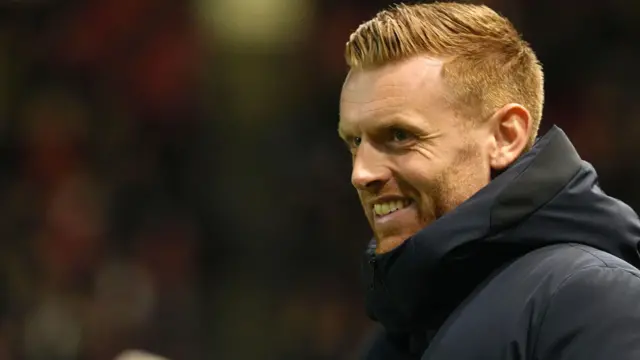 Ed Still, wearing a hooded jacket, smiles at the end of the win against Bristol City at Ashton Gate in February
