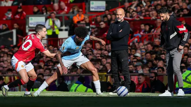 Manchester United boss Ruben Amorim and Manchester City counterpart Pep Guardiola watch Diogo Dalot and Nico O'Reilly battle for possession