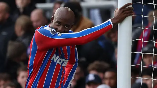 Jean-Philippe Mateta leans against goal post looking dejected