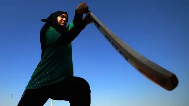 A Saudi women's cricketer plays a drive while warming-up for a game