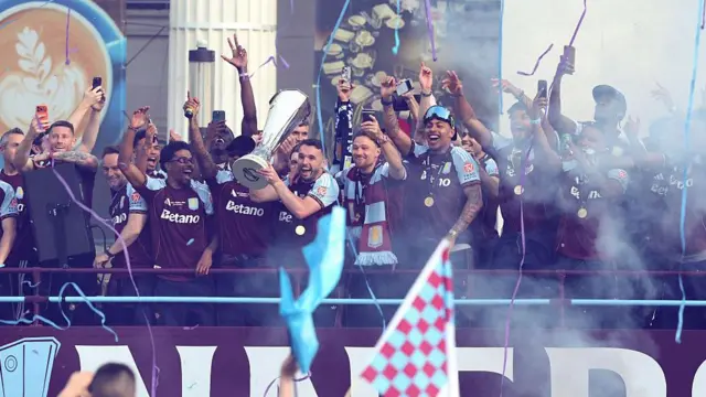 John McGinn holds trophy on tour bus as confetti strings come down