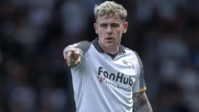 Sammie Szmodics wearing a white Derby shirt points forward
