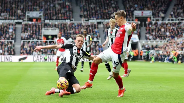 Leandro Trossard of Arsenal is challenged by Sean Longstaff of Newcastle United during the Premier League match between Newcastle United FC and Arsenal FC at St James' Park