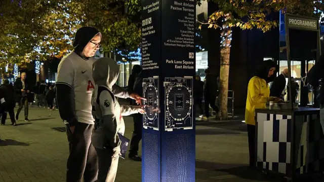 Two fans look at map of ground outside Tottenham Hotspur Stadium