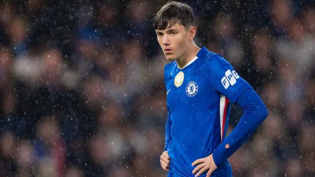 Reggie Walsh, wearing Chelsea's blue home kit, stands with his hands on his hips during the game against Ajax