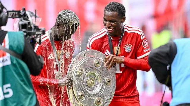 Nicolas Jackson enjoying Bayern Munich's title celebrations with a trophy and smiling